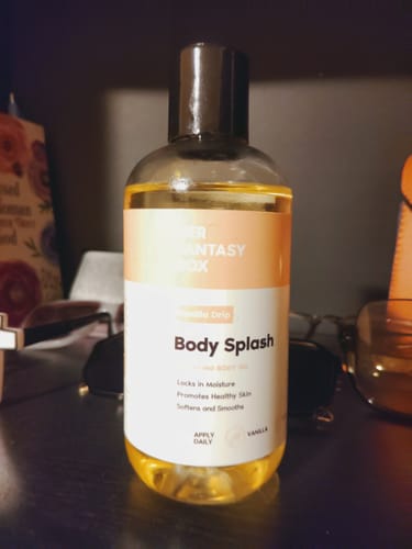 Customer's Vanilla Drip Body Splash body oil in a clear bottle, sitting on a dark shelf.