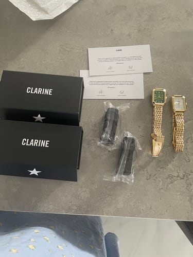 Customer's two CLAIRE DE MAINS watches with gold-colored bands, laid out next to their black packaging boxes.