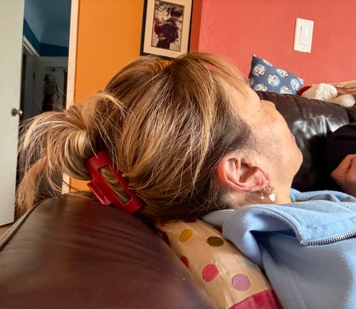Reviewer comfortably leaning back on a couch with their hair secured by a red cloud clip.