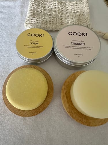 Reviewer's Lemon Shampoo Bar Bundle, with the shampoo and conditioner bars on bamboo dishes beside their tins.