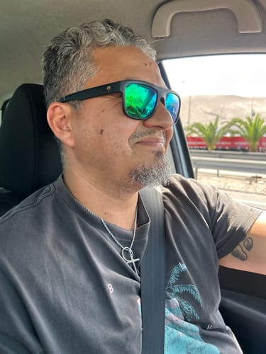 Un cliente sonriendo en un coche, luciendo su Crucifix Pendant con una cadena de cuerda.