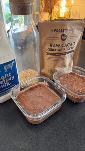 Customer's Raw Ceremonial Cacao bag next to two glass bowls of prepared, chocolatey overnight oats.