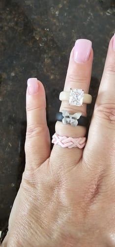 Reviewer wearing the black silicone Butterfly Collection ring with a silver butterfly, stacked with two other rings.