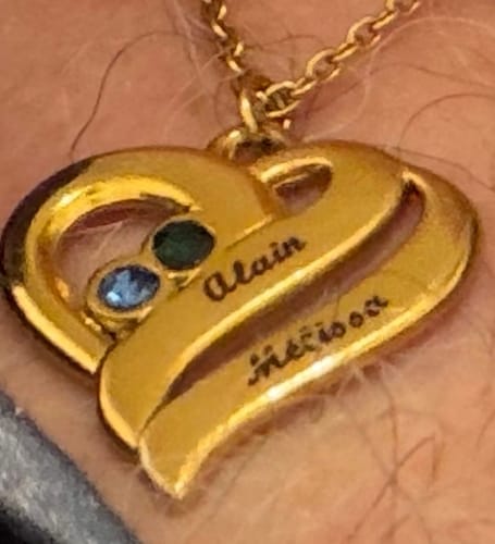 Nahaufnahme der goldenen Halskette mit vereinten Herzen eines Kunden, personalisiert mit zwei Namen und zwei Geburtssteinen.