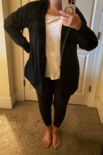 Reviewer wears the black Ryann Hoodie open, showing its relaxed fit over a white shirt and leggings.
