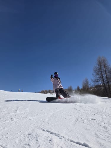 Customer snowboarding down a snowy slope wearing the baggy, coffee-colored snow pants.