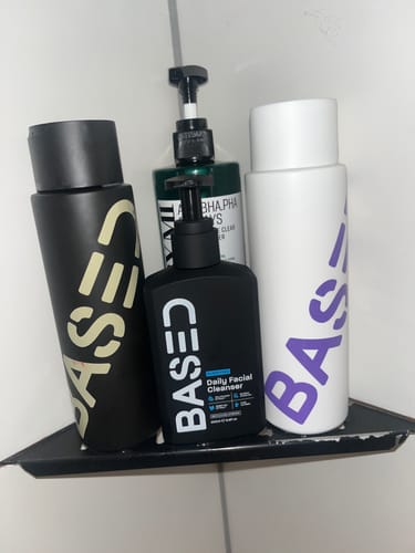 Customer's Shower Duo shampoo and conditioner bottles arranged on a black shower shelf.