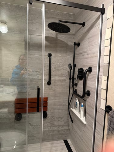 Customer's black 2-Handle Shower System installed in a tiled, ADA-accessible shower with grab bars and a fold-down seat.