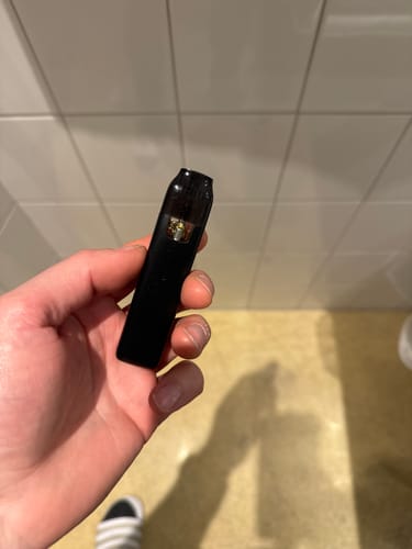 Ein Kunde hält einen schwarzen THC-Vape mit sichtbarer Kartusche in der Hand.
