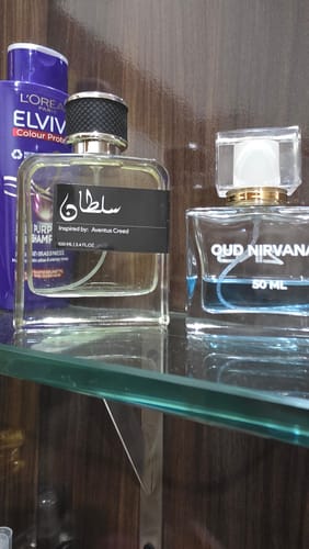Customer's Oud Nirvana perfume from the OUD Supreme BUNDLE on a glass shelf next to other fragrances.