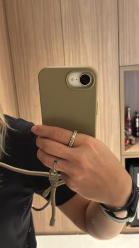 Cliente mostrando sua Case Areia em um celular, com a alça da mesma cor conectada.
