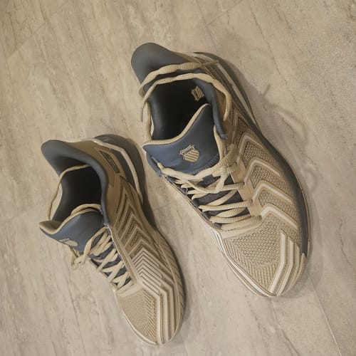 A customer's new pair of ULTRASHOT 4 shoes in pale khaki and gray, shown from above on a tiled floor.