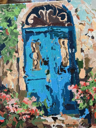 לקוח מציג את התוצאה הסופית של ערכת הצביעה לפי מספרים: ציור צבעוני של דלת כחולה מוקפת בפרחים.