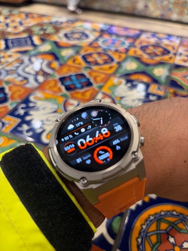 Reviewer's Gard Pro Ultra 3 smartwatch with a silver case and orange band shown on a wrist.