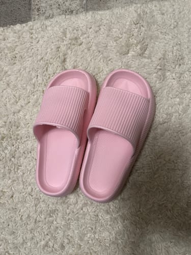 Customer's pair of pink Cloudies Orthopedic Slippers resting on a fluffy white rug.