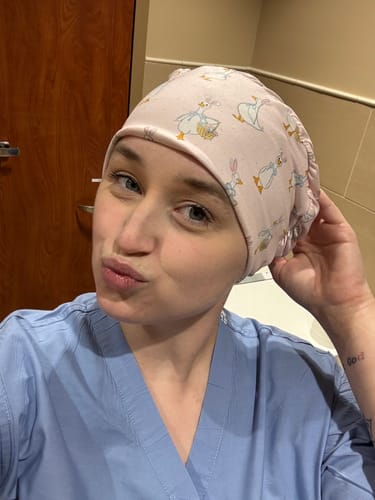 Customer taking a selfie in blue scrubs, wearing the pink DuoStyle Scrub Hat with an Easter Goose pattern.