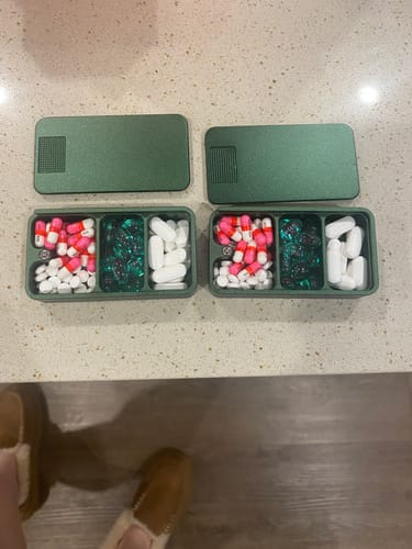 Reviewer's 2-Pack Bundle of green pill cases shown open on a counter and filled with various pills.