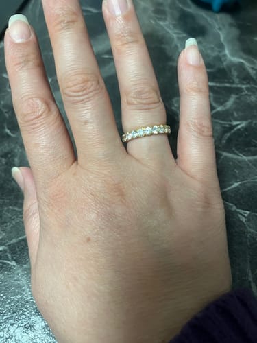 Eine Kundin zeigt den goldenen Amia Ring mit funkelnden Steinen an ihrer Hand.