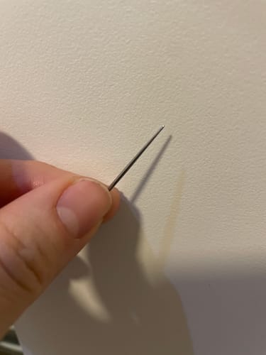 Close-up of a reviewer holding the thin metal Flatback Insertion Taper.