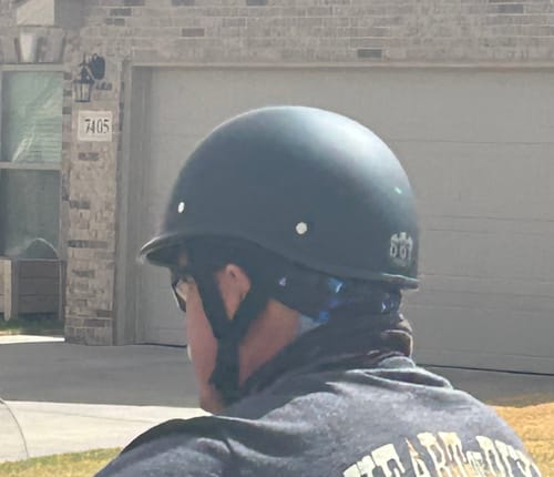 A view from behind the reviewer, showing the rear shape of the matte black Low Profile Polo Helmet.