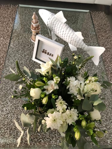 Customer's White Delight Posy of lovely white flowers and green leaves displayed on a glass coffee table.