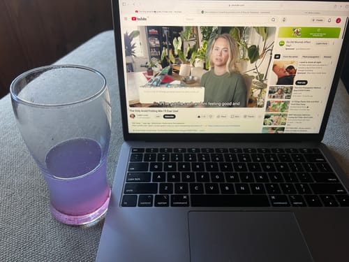 Customer's glass of purple Blackcurrant Apple probiotic blend on a table next to an open laptop.