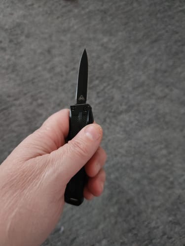 A customer holds the small black VT Mini Stinger OTF Knife in their hand with the blade extended.