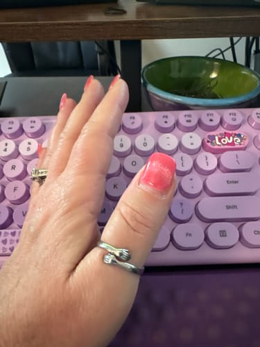A customer wearing the silver Hug From Heaven Ring on their thumb over a purple keyboard.