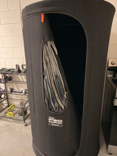 Customer's black Sauna Pod 2.0 standing upright in a home gym, showing the large entrance.
