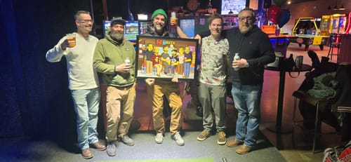 Reviewer's photo of five men holding their framed Turn Me Yellow portrait in a restaurant.