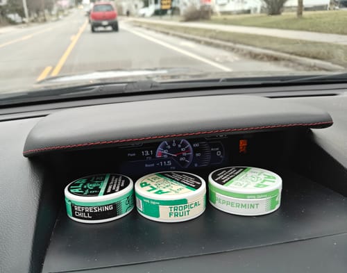 Customer's Refreshing Chill Nicotine Pouches tin with two other flavors on a car dashboard.