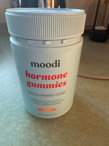 Customer's light blue jar of peach-flavored Hormone Gummies sitting on a kitchen counter.