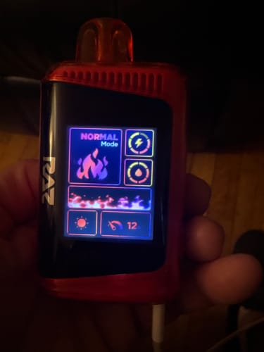 Customer holding the red Raz LTX vape with its bright screen displaying 'NORMAL Mode'.