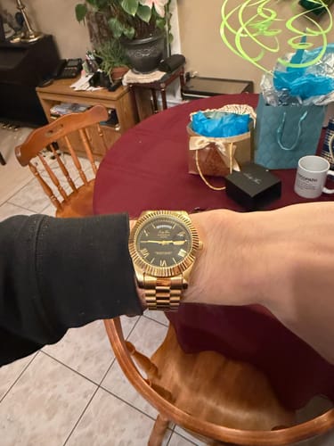 A customer wears their gold Lucky Fours® Santos watch with a black dial.