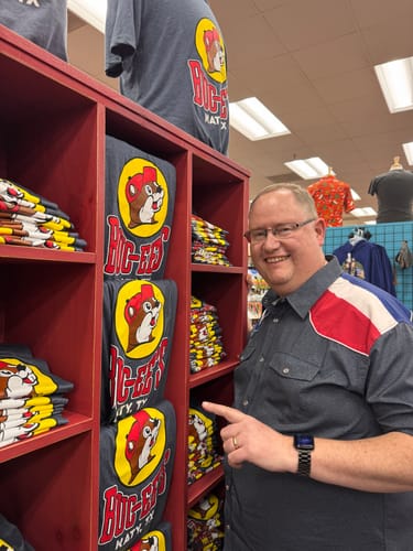 Customer wearing The Stars at Night Roper Short Sleeve Shirt while pointing at a merchandise display in a store.