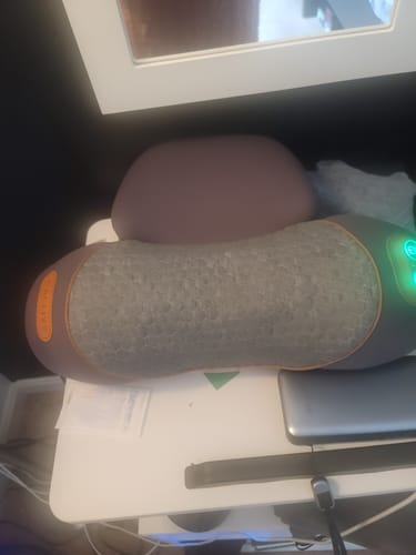 Customer's Original Callixe Thera Pillow resting on a desk with its green power light illuminated.