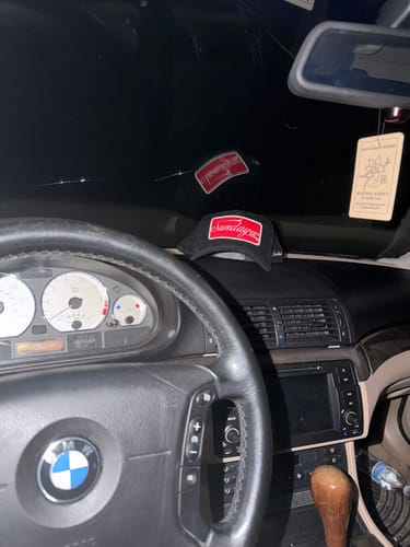 Customer's VINTAGE SNAPBACK with a red logo sitting on the dashboard of a car at night.