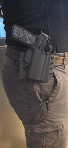 Reviewer wearing the black SPARA holster, showing its snug fit on their hip with a pistol inside.