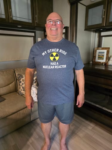 A reviewer wearing the blue 'My Other Ride Had A Nuclear Reactor' t-shirt indoors.