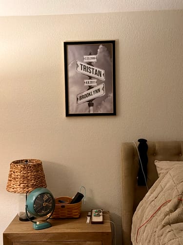Customer's framed 'Couples Date of Love' canvas with a street sign design hanging on a bedroom wall.