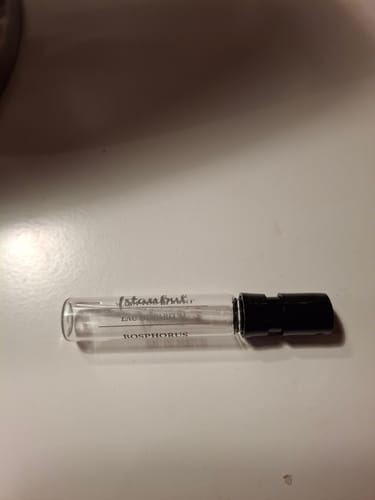 Klant toont het lege proefmonster van het Istanbul Bosphorus parfum op een wit oppervlak.