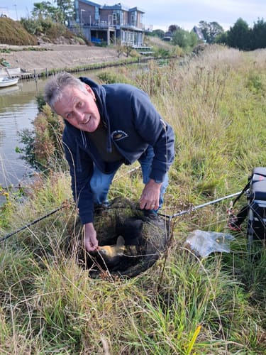 Klant toont een grote brasem in een schepnet, gevangen met behulp van het BRASEM CARAMEL lokmiddel.