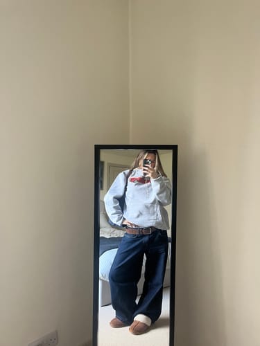 Reviewer in a mirror selfie wearing the baggy drop top grey hoodie.