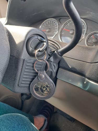 Reviewer's 44-year sobriety medallion in a black keychain holder hanging from a car's ignition.