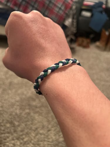 Customer wearing the woven DAVID Bracelet, showing its blue, green, and white strands.