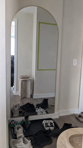 Customer's Gold Full Length Arch Mirror leaning against a wall in an entryway with shoes in front.