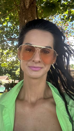 Cliente usando os Óculos Sicilia grandes com lentes laranja em uma selfie ao ar livre.