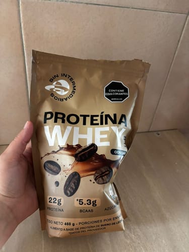 Cliente mostrando el empaque café de la Proteína Aislada sabor café.