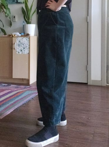 Customer showing a side view of the dark green corduroy harem pants, highlighting the fit and ankle length.