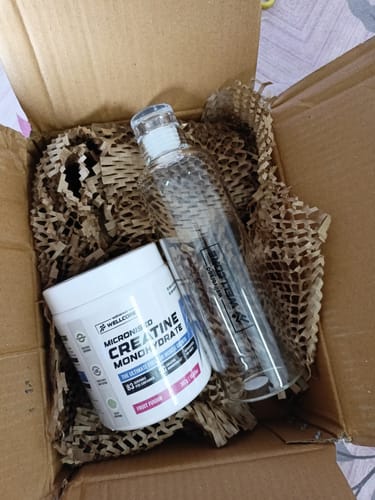 Customer unboxing the Wellcore Micronised Creatine Monohydrate and the included premium glass bottle from a cardboard box.
